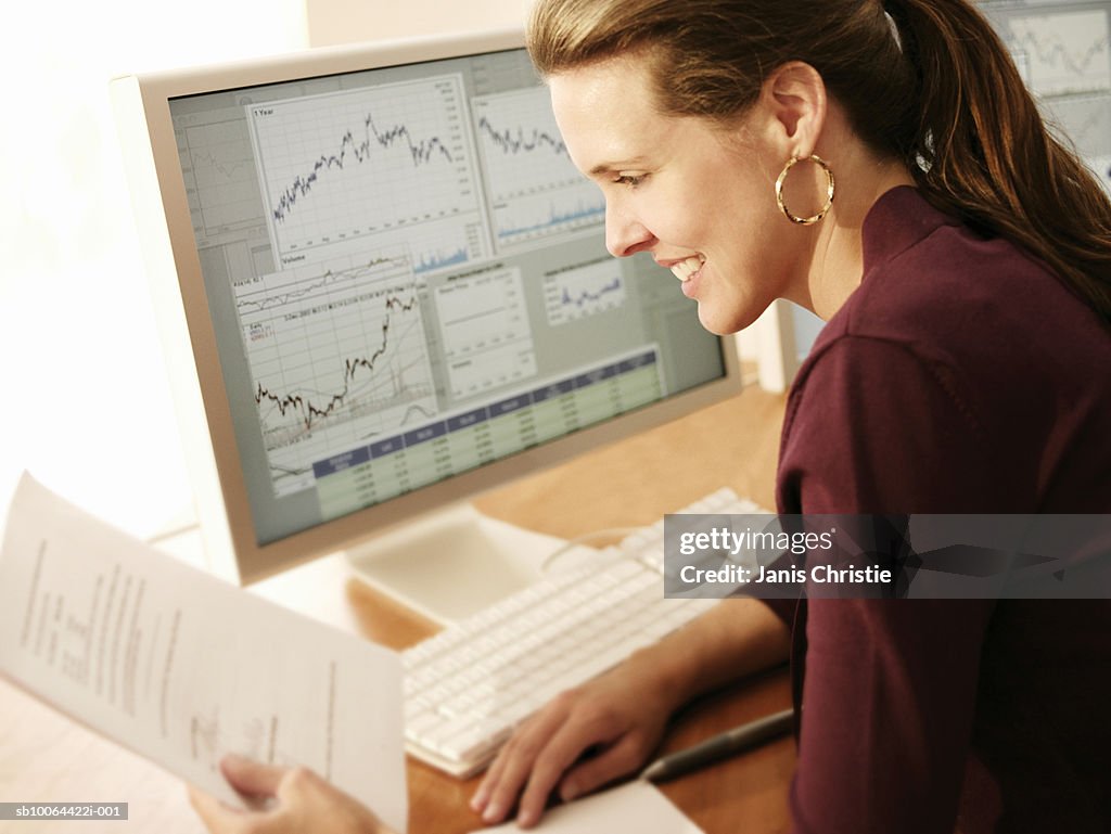 Woman sitting at desk with computer, reading documents