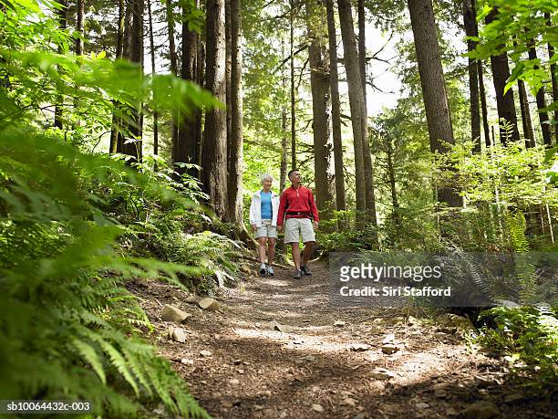 mature couple hiking in forest, smiling - shorts down stock pictures, royalty-free photos & images