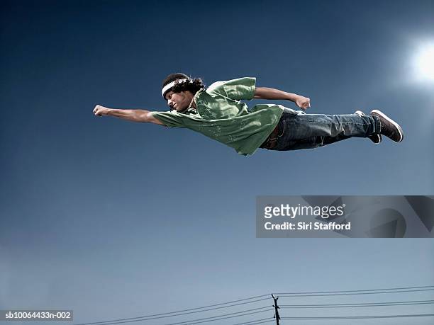 teenage boy (16-17) flying in mid air, low angle view - volare foto e immagini stock