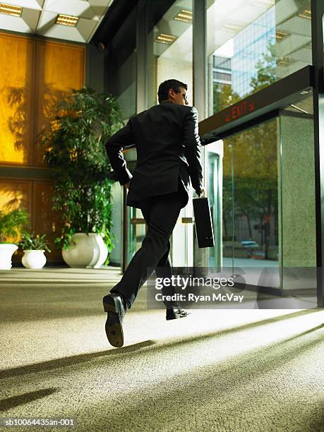 businessman carrying briefcase leaving office building, rear view - leaving office stock pictures, royalty-free photos & images