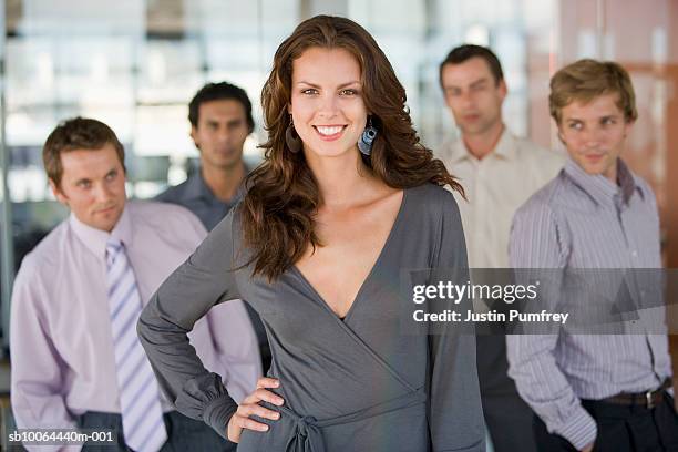 portrait of young woman, four men in background looking at her - reputation stock pictures, royalty-free photos & images