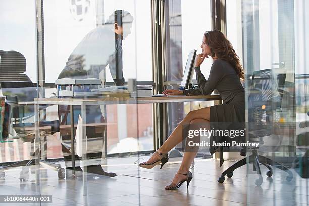 man and woman sitting in office, view from behind glass wall - flirting stockfoto's en -beelden