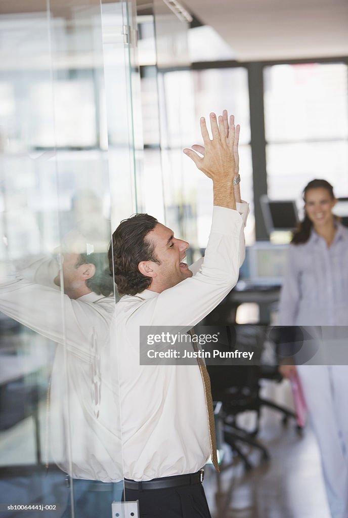 Businessman in office laughing with arms raised