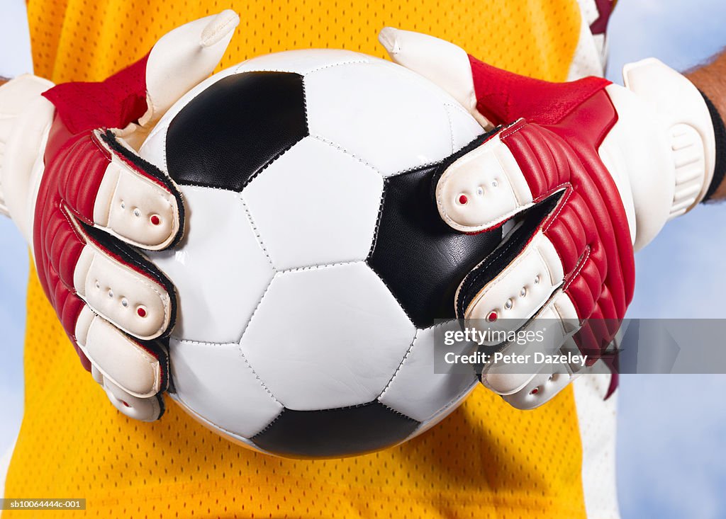 Goalkeeper holding football, mid section, close-up