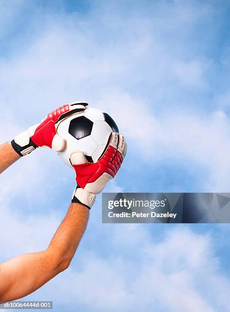 goalkeeper catching football against sky, close-up of arms and hands - トレーニンググローブ ストックフォトと画像