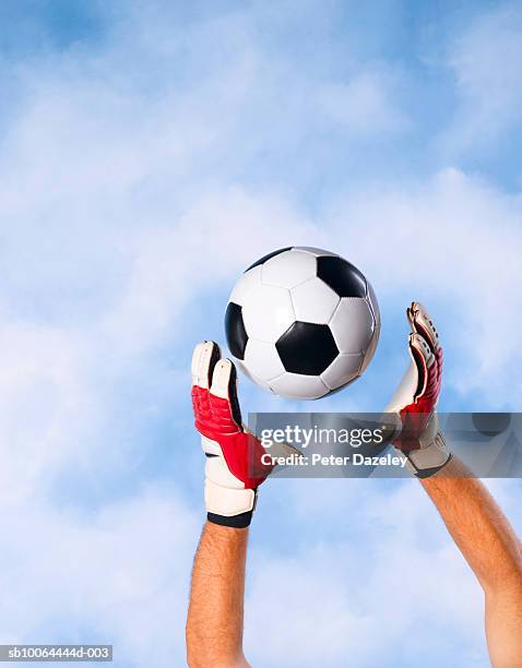 goalkeeper catching football against sky, close-up of hands and arms - goalkeeper gloves stock pictures, royalty-free photos & images