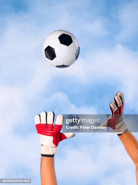 goalkeeper catching football against sky, close-up of arms and hands - soccer glove stock pictures, royalty-free photos & images