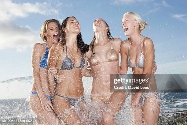 two young women and two teenage girls (14-15, 16-17)  playing in ocean - femme décolleté photos et images de collection