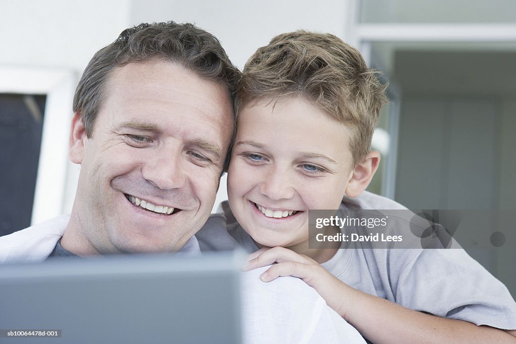 Boy (8-9) and father using laptop on sofa, close-up