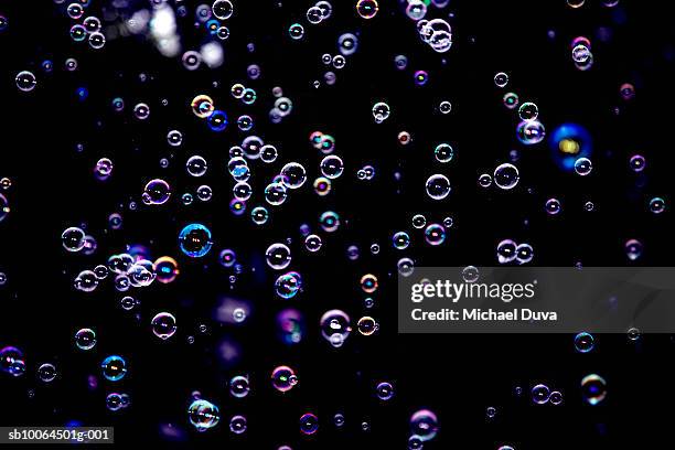 purple bubbles floating on black background - soap sud stock pictures, royalty-free photos & images