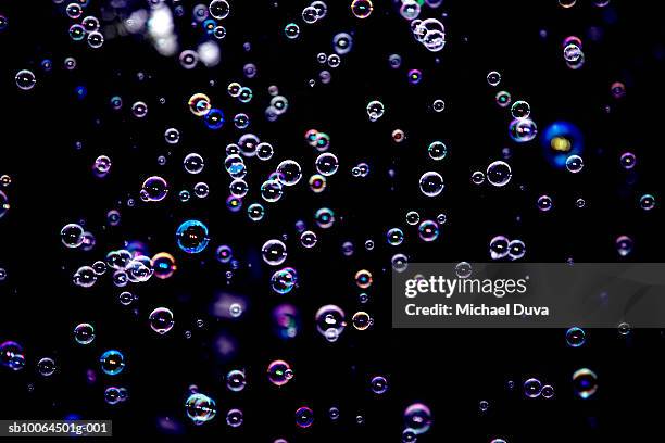 purple bubbles floating on black background - soap suds stock pictures, royalty-free photos & images