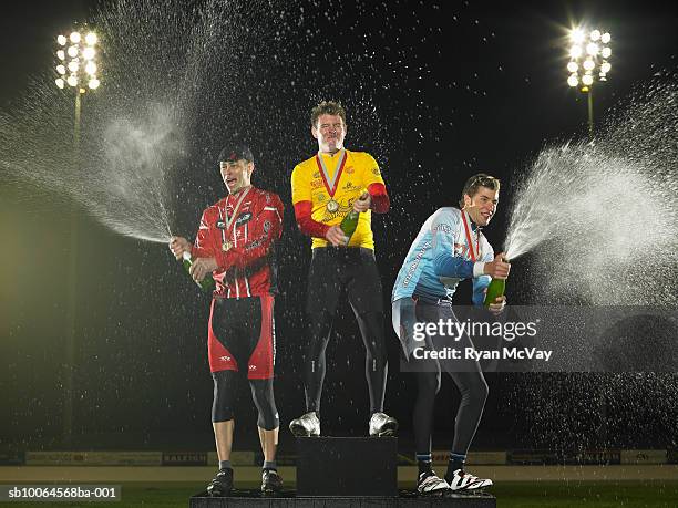 cyclists standing on podium, spraying champagne - second place fotografías e imágenes de stock