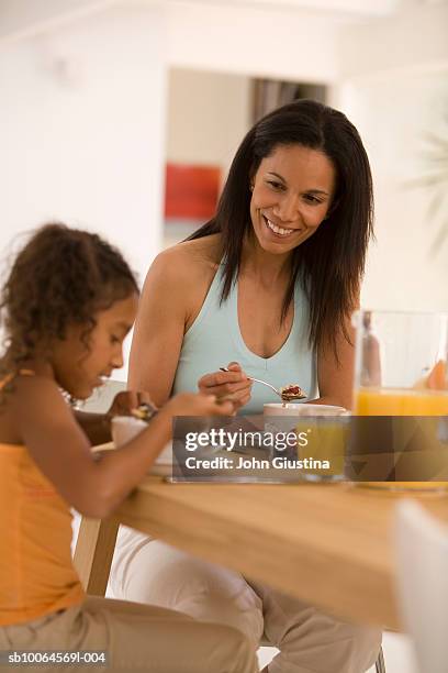 mother and daughter (6-7) at table eating breakfast - family orange juice stockfoto's en -beelden