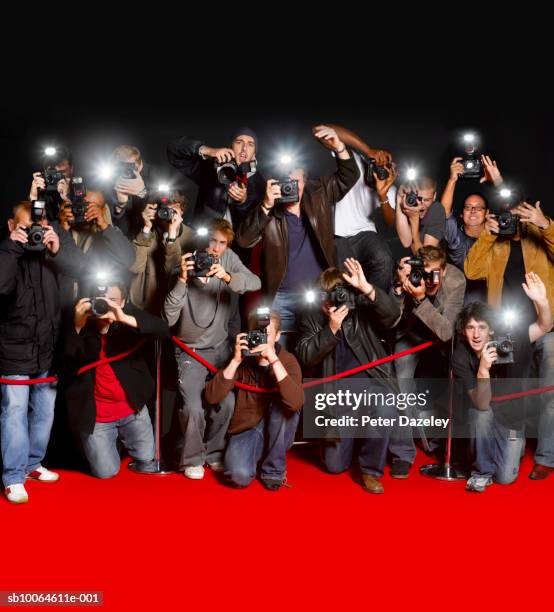 paparazzi behind cordon at premiere using flash cameras - estreno fotografías e imágenes de stock