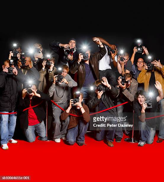 paparazzi behind cordon at premiere using flash cameras - red carpet foto e immagini stock