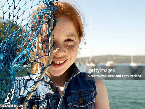 girl (10-11) covering face with fishing net, portrait - fischnetz stock-fotos und bilder