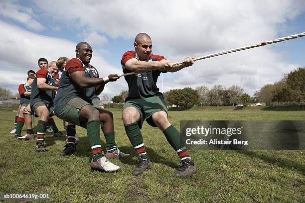 rugby players playing tug of war on field - rugby competition stockfoto's en -beelden