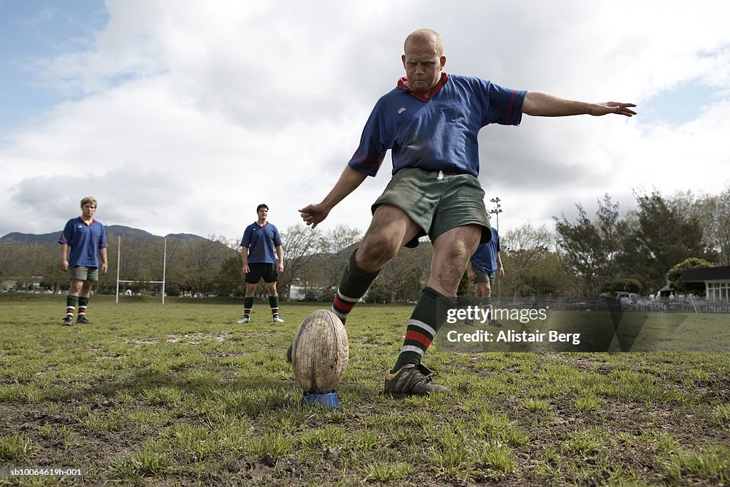 Rugby player kicking ball on sports field, low angle view