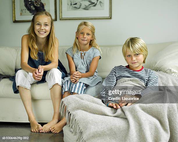 brother and sisters (8-14) sitting on sofa, smiling, portrait - tre syskon bildbanksfoton och bilder