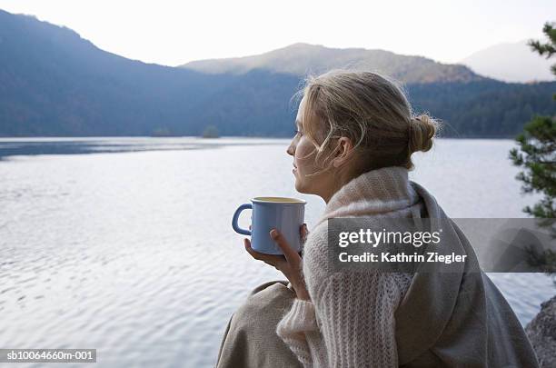 young woman wrapped in blanket holding coffee cup - escapism stock-fotos und bilder