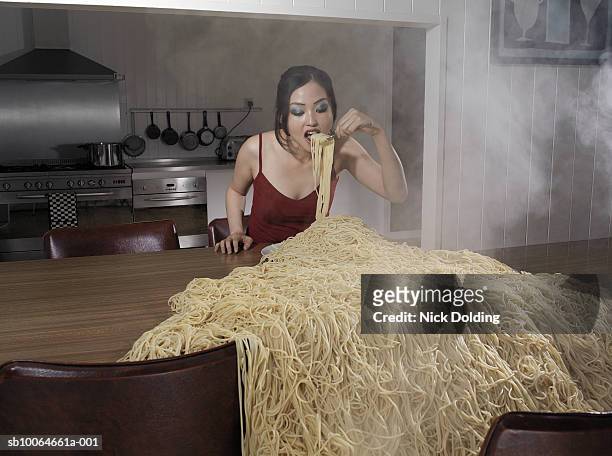 woman standing at table eating heap of spaghetti - abundance stock-fotos und bilder