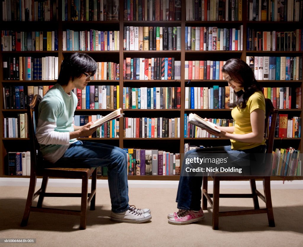 Man and woman reading in library, side view