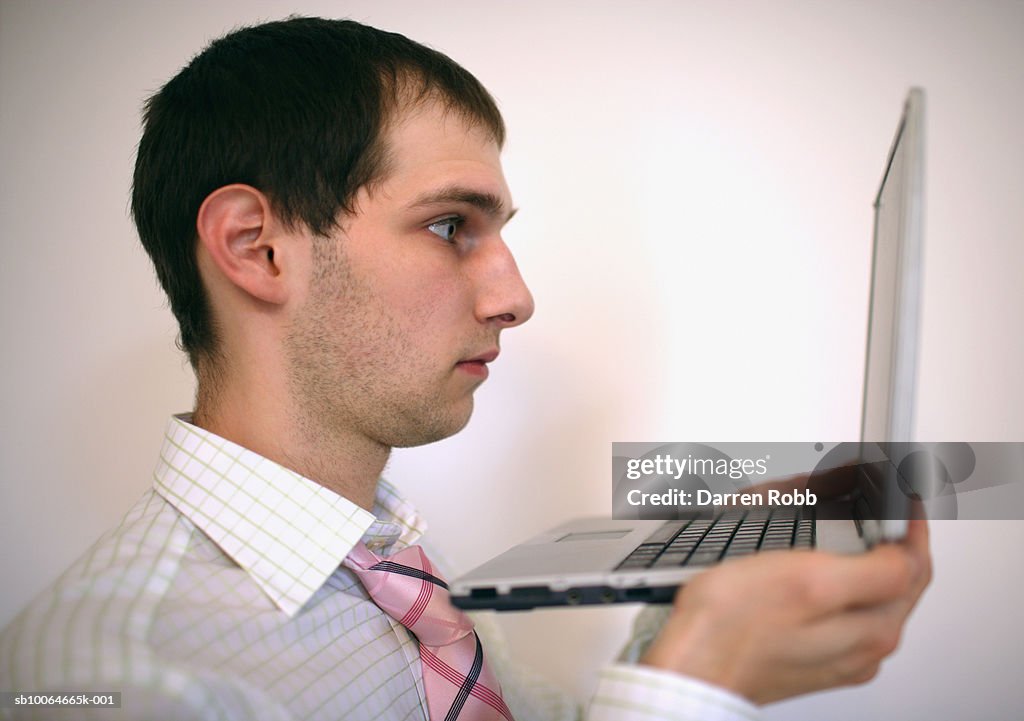 Young businessman holding laptop, side view
