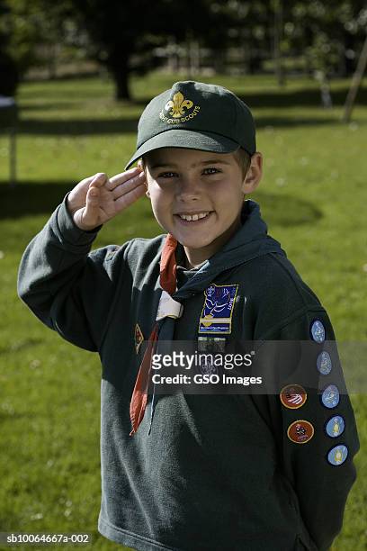 boy wearing cub scout uniform, saluting, smiling, portrait - scouts stockfoto's en -beelden