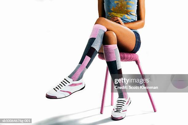 young woman with high socks sitting against white background, low section - benen over elkaar geslagen stockfoto's en -beelden