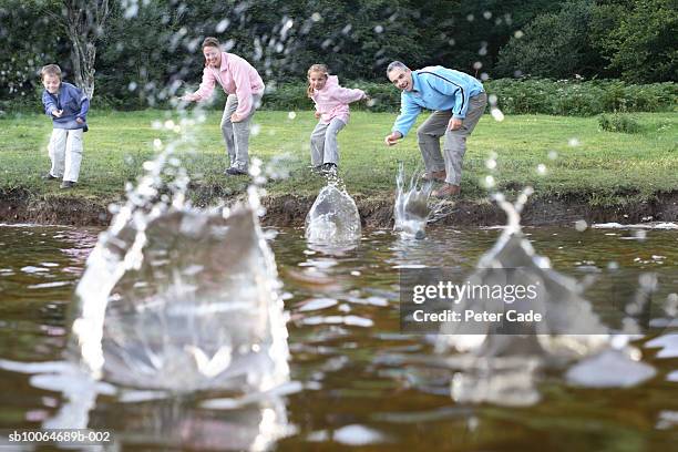 family with children (6-8) skipping stones on lake, focus on family (surface level) - skimming stones stock pictures, royalty-free photos & images