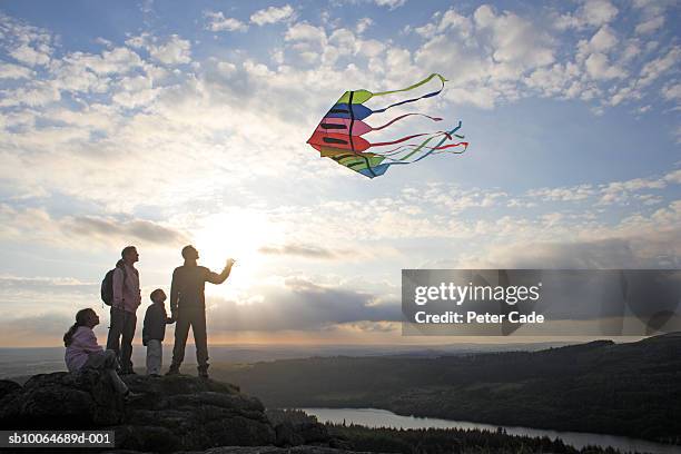 family with children (6-8) flying kite on moors at sunset - watching sunset stock pictures, royalty-free photos & images