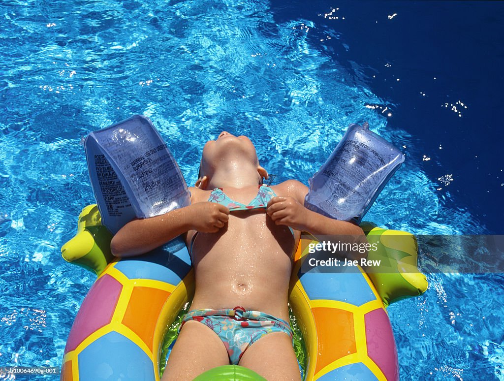 Girl (4-5 years) floating on inflatable ring in pool, elevated view