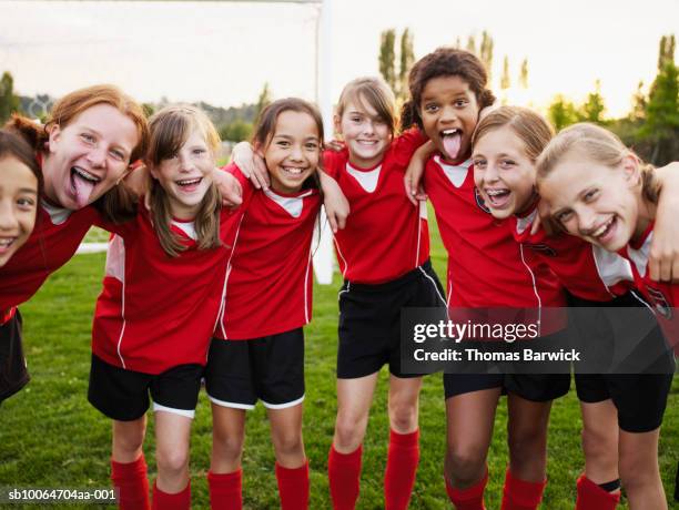 eight female football players (10-13) standing in pitch, making faces, in huddle formation - soccer girl stockfoto's en -beelden