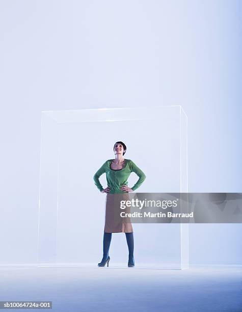 woman standing in glass cabinet with hand on hip - glass box stock pictures, royalty-free photos & images