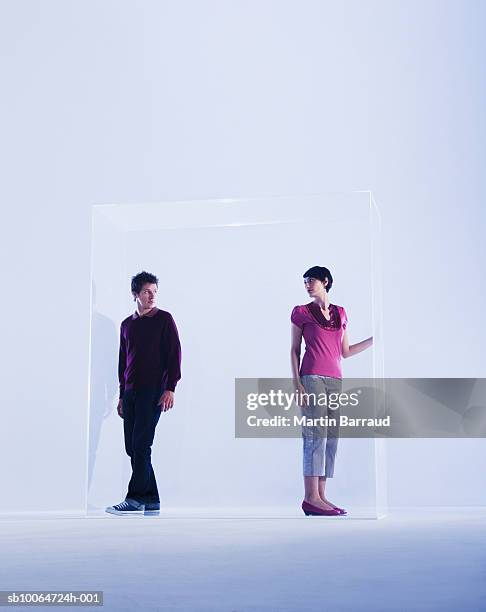 couple standing in glass cabinet - glass box stockfoto's en -beelden