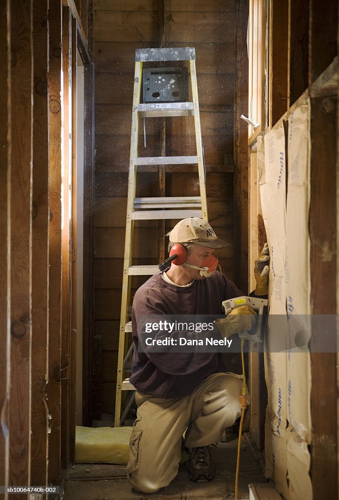 Construction worker installing insulation in house