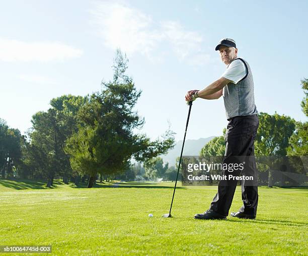 portrait of mature man on golf course leaning on club, side view - golf short iron stock pictures, royalty-free photos & images