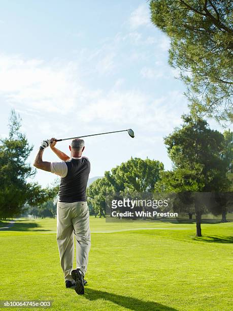 senior man on golf course swinging, rear view - golf short iron stock pictures, royalty-free photos & images