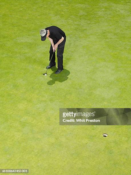 mature male golfer putting golf ball, elevated view - golf short iron stock pictures, royalty-free photos & images