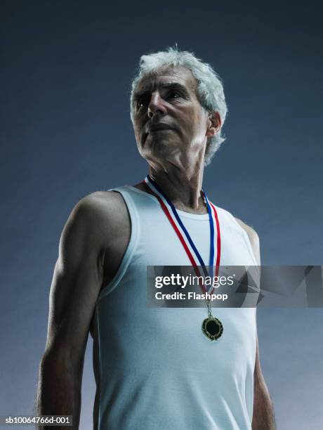 senior man wearing medal, studio shot - medalist stock-fotos und bilder