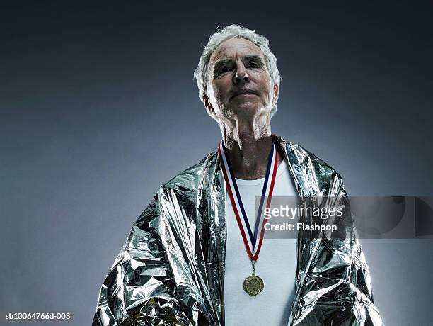 senior man wearing medal and foil blanket, studio shot - marathon medal stock pictures, royalty-free photos & images