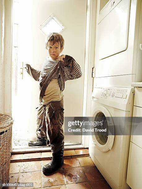 portrait of boy (8-9) in dirty clothes standing in front of washing machine - kids mud stock pictures, royalty-free photos & images