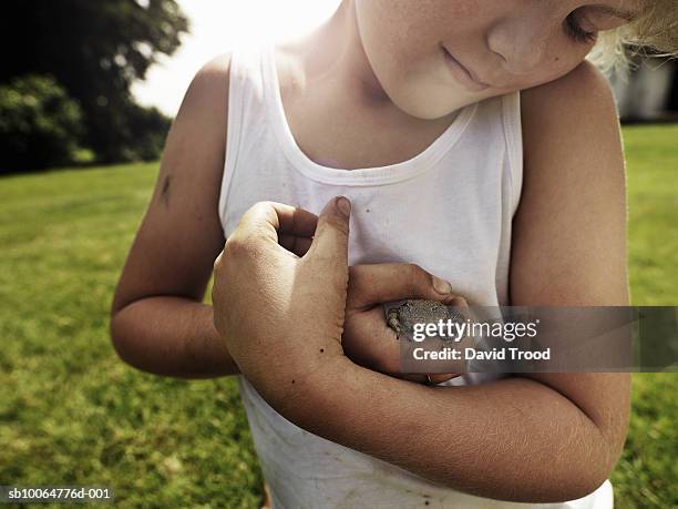 boy (8-9) holding toad in garden - camisa sin mangas fotografías e imágenes de stock