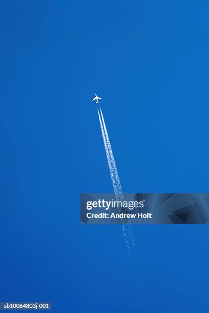 aeroplane leaving vapour trail in clear blue sky, low angle view - trainee photos et images de collection
