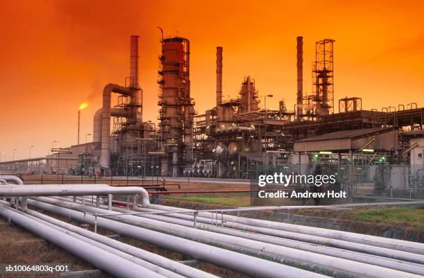 flare stack burning waste gas at oil refinery - ölraffinerie stock-fotos und bilder