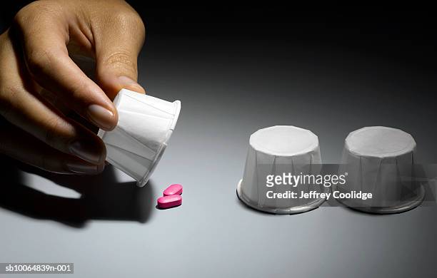 game of chance, female hand lifting 1 of 3 paper cups showing 2 pills, close-up - game 2 2 stock pictures, royalty-free photos & images