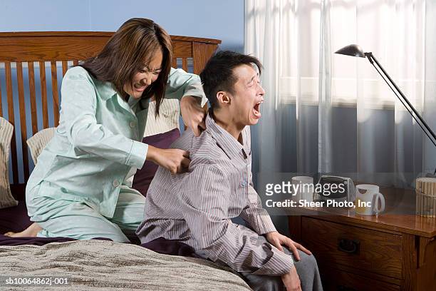 woman massaging man sitting on bed - massage funny stock pictures, royalty-free photos & images