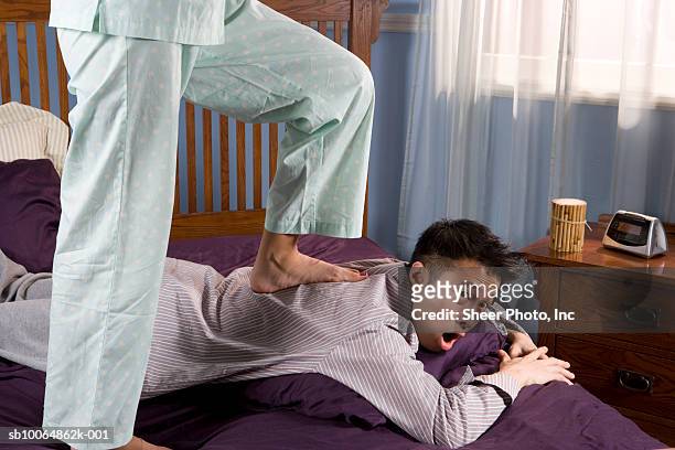 woman (low section) stepping on man lying on bed - massage funny stock pictures, royalty-free photos & images