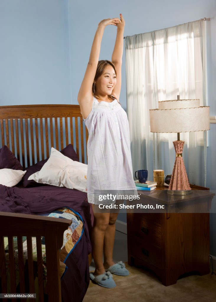 Woman stretching standing by bed