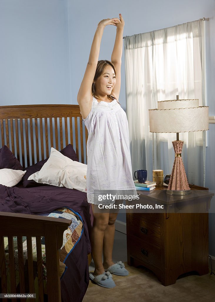 Woman stretching standing by bed